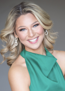 A woman in a green dress smiling. 